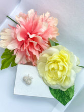 Load image into Gallery viewer, Knot earrings from top view with flowers as background
